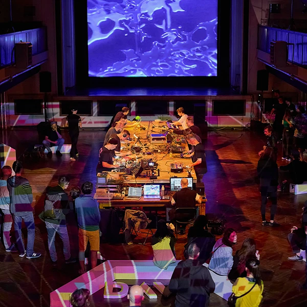 concert hall with synthesizer artists and a big screen with visuals